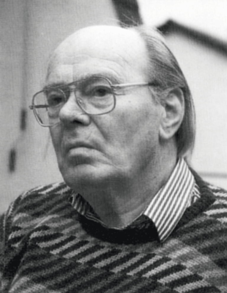 Peter Recker Porträt eines älteren Mannes mit Brille und kurzen Haaren, bekleidet mit einem gestreiften Pullover.